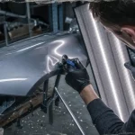 Debosseleur sans peinture en atelier, aile de voiture sur chandelles