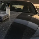 Nettoyage voiture sans eau : microfibre et flacon sur carrosserie sèche